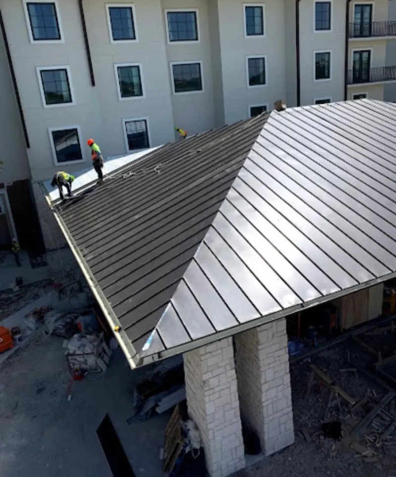 Crew installing standing seam metal roof panels on a commercial project in Johnston